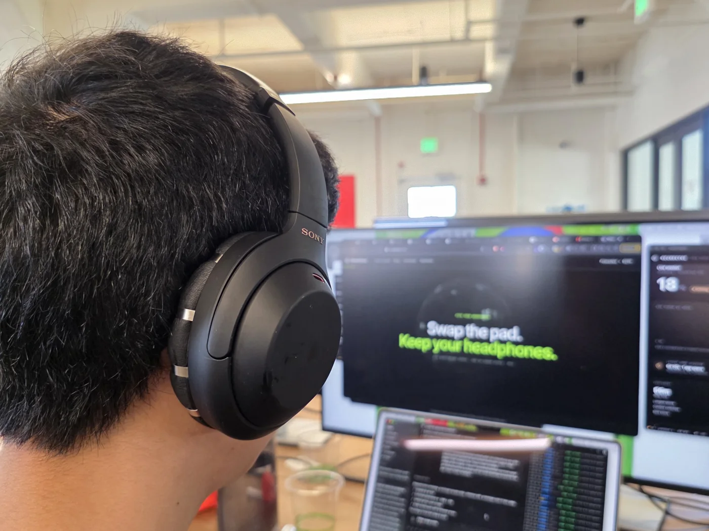 A NeuroFocus tester wearing the real EEG ear pad while working at a laptop